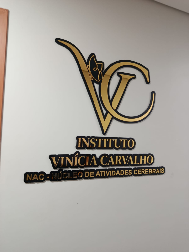 Letreiro interno em acrílico preto e dourado na parede de uma recepção
